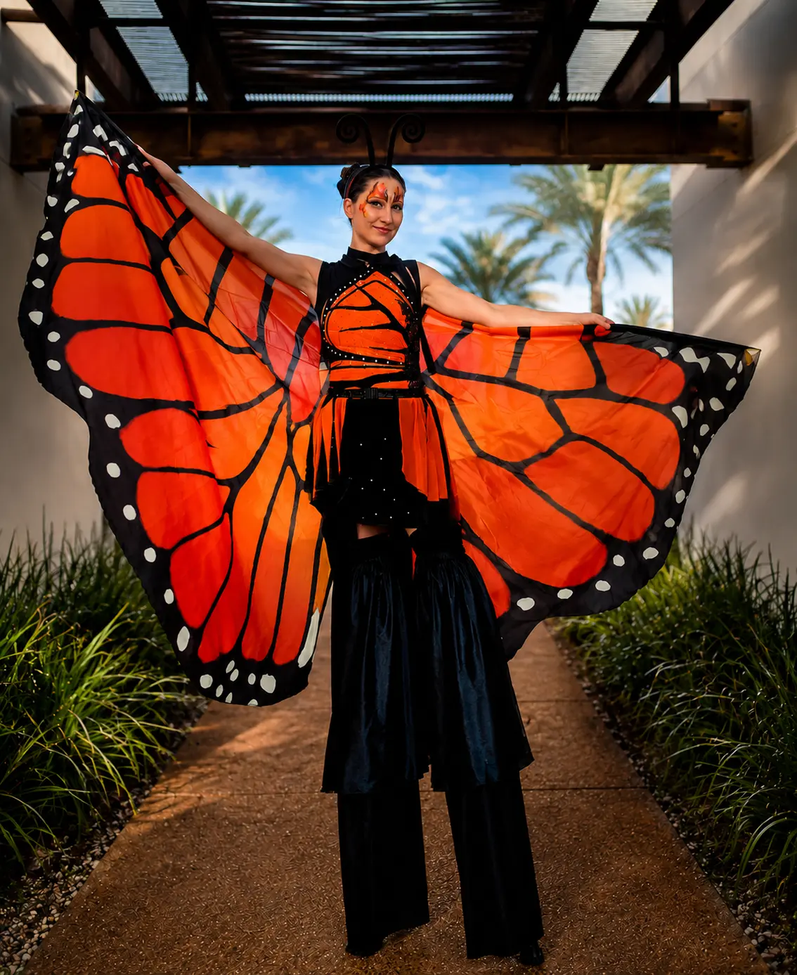 Tabitha on stilts in an orange monarch butterfly costume
