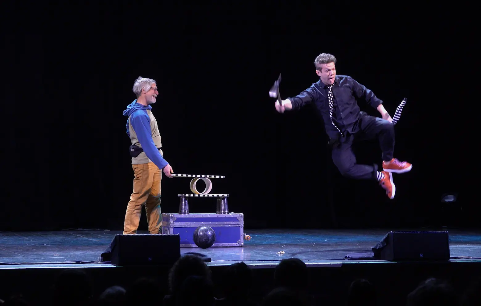 Comedy danger-show performer leaping onstage beside balancing props
