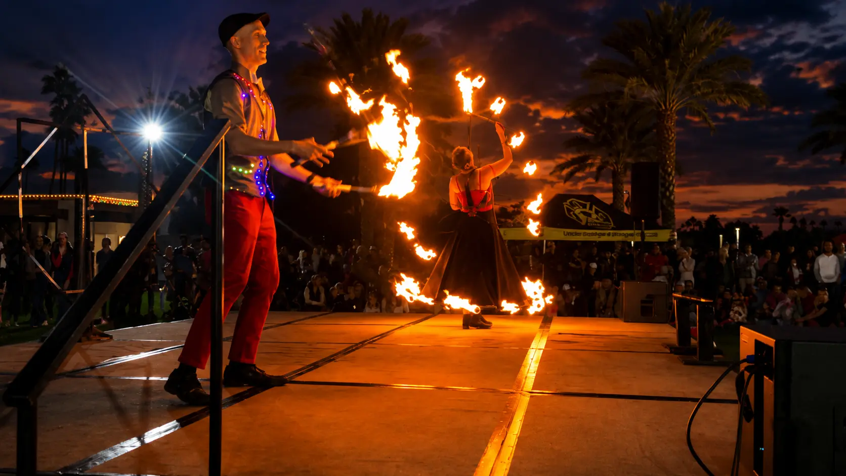 Dan juggling fire clubs while Tabitha performs with fire on an outdoor stage