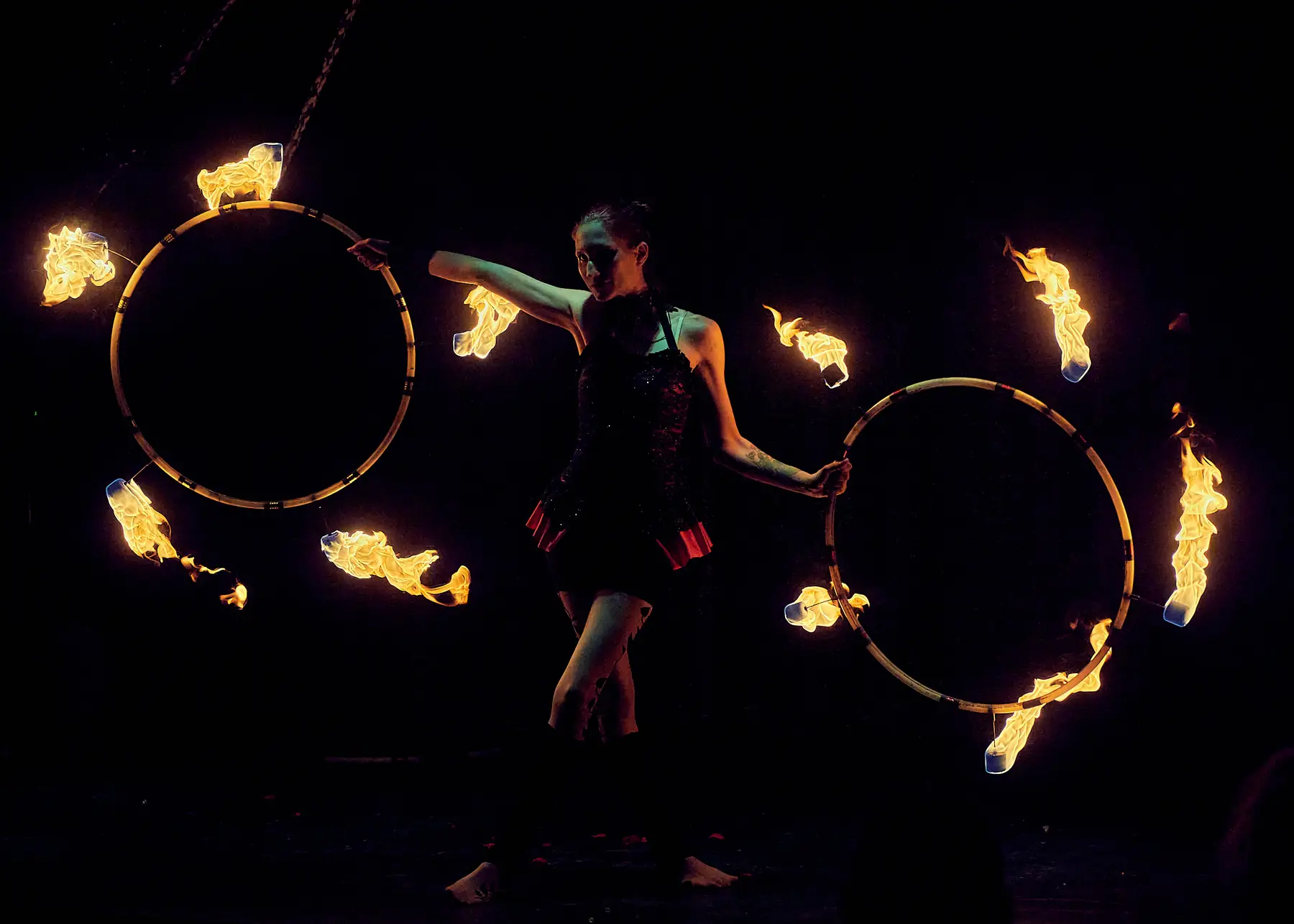 Tabitha performing with two flaming hoops against a dark stage