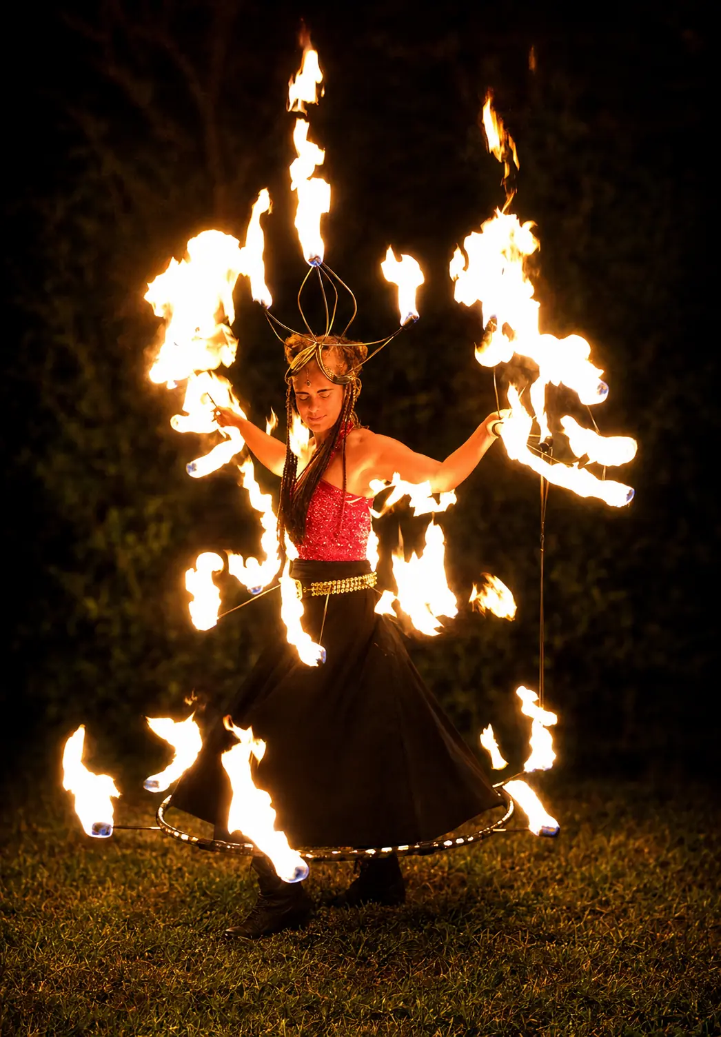 Trisha performing with a flaming headpiece, fire fans and a circular fire skirt ensemble