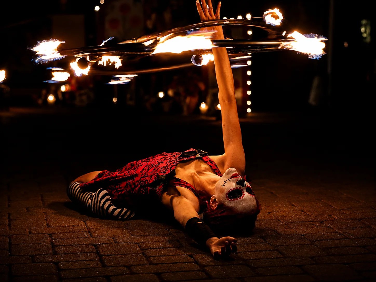 Tabitha balancing with multiple flaming hoops during a fire show