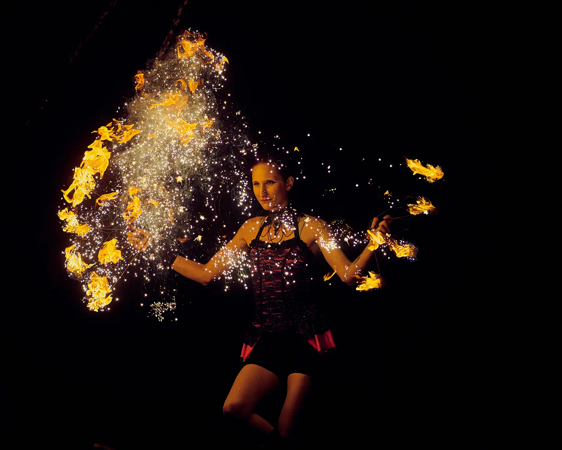 Tabitha performing with spark-emitting fire fans against a black background