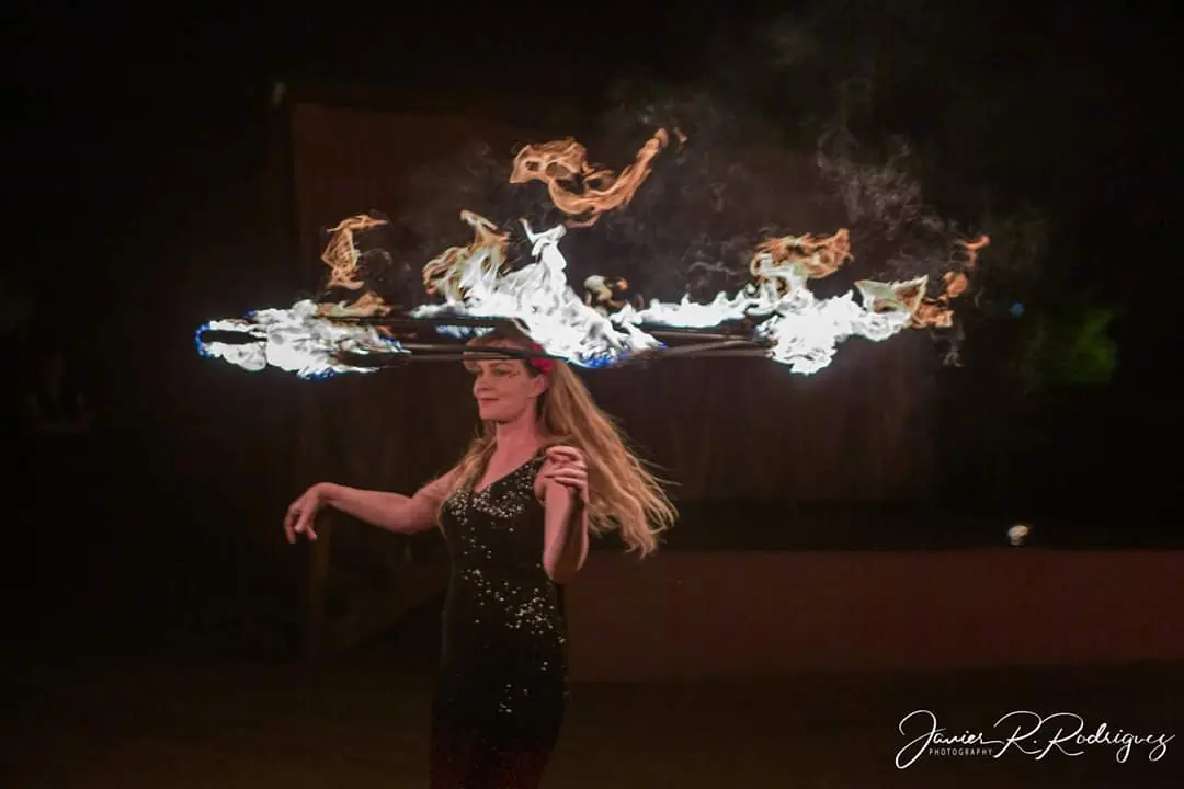 Trisha balancing a star-shaped fire prop on her head during a nighttime show