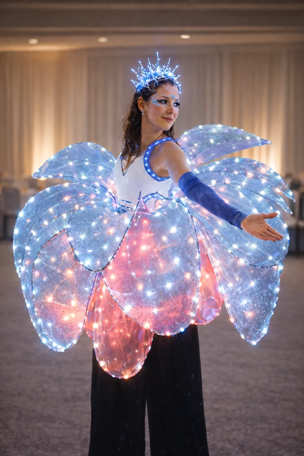 Performer posing in a blue and pink illuminated flower-petal stilt costume