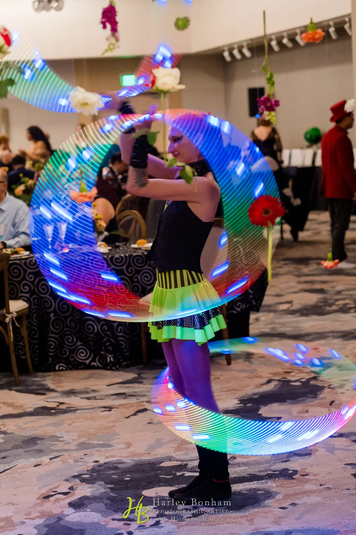 Tabitha spinning multiple LED hoops while roaming among guests at an indoor event