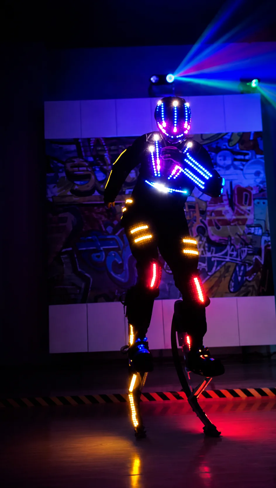 Performer presenting a programmable LED costume while balancing on jumping stilts