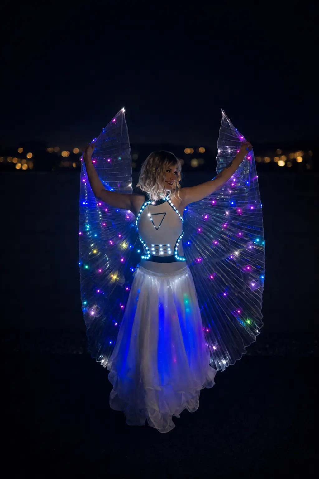 Performer presenting a white illuminated wing costume with multicolored LEDs