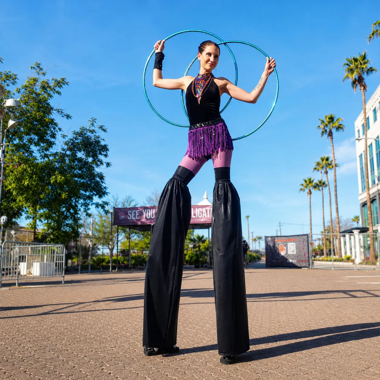 Tabitha on stilts with illuminated hoops in a purple Mardi Gras costume