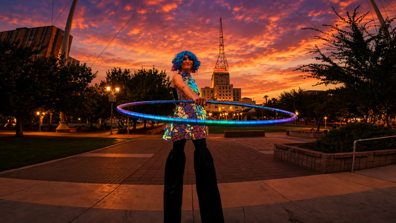 Tabitha performing with an illuminated hoop in a reflective costume at sunset