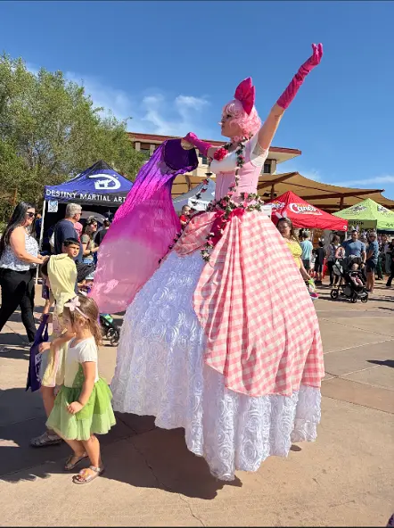 Stilt performer greeting guests in a pink floral garden costume