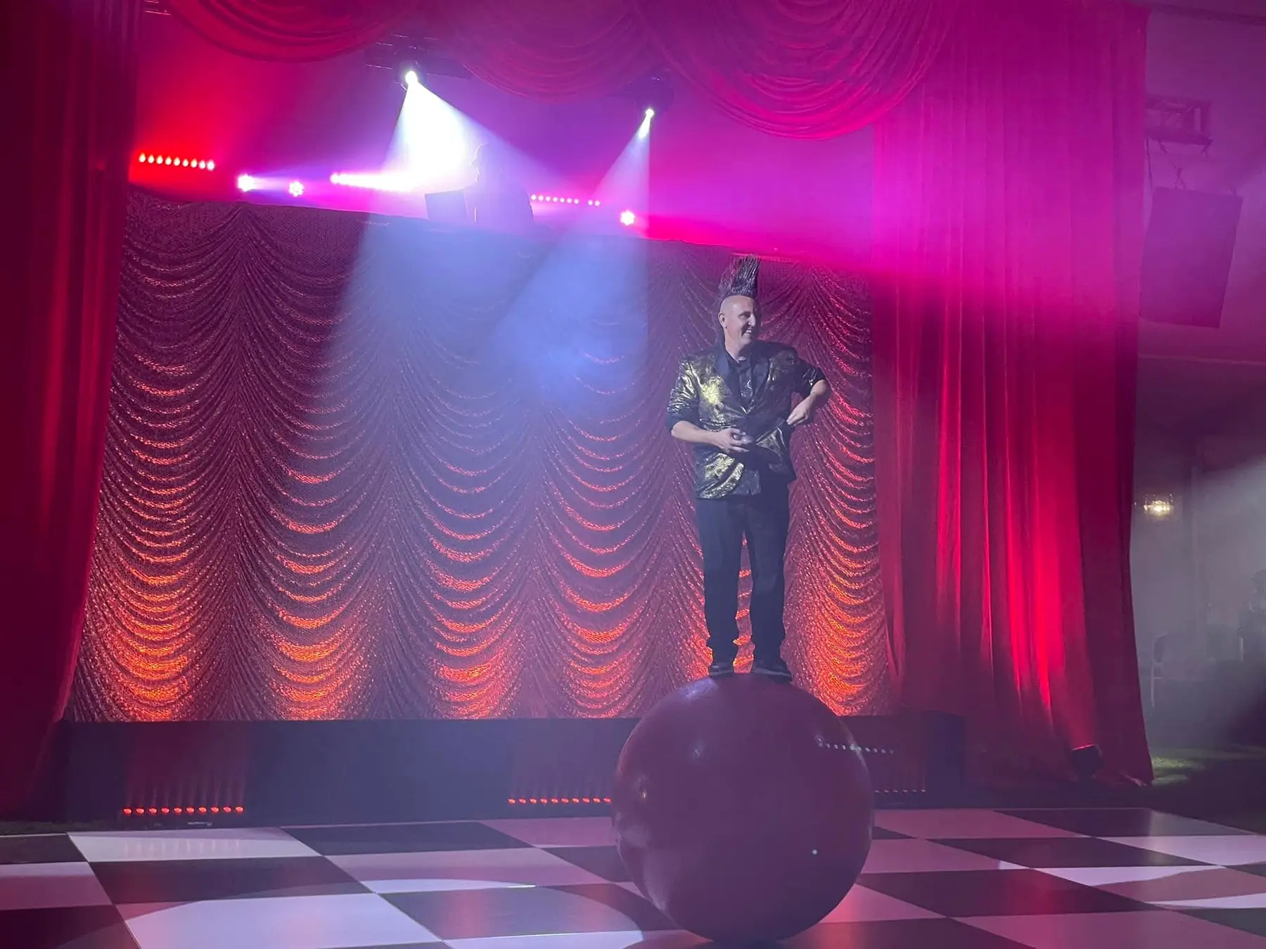 Stevie balancing on a walking globe under magenta stage lights