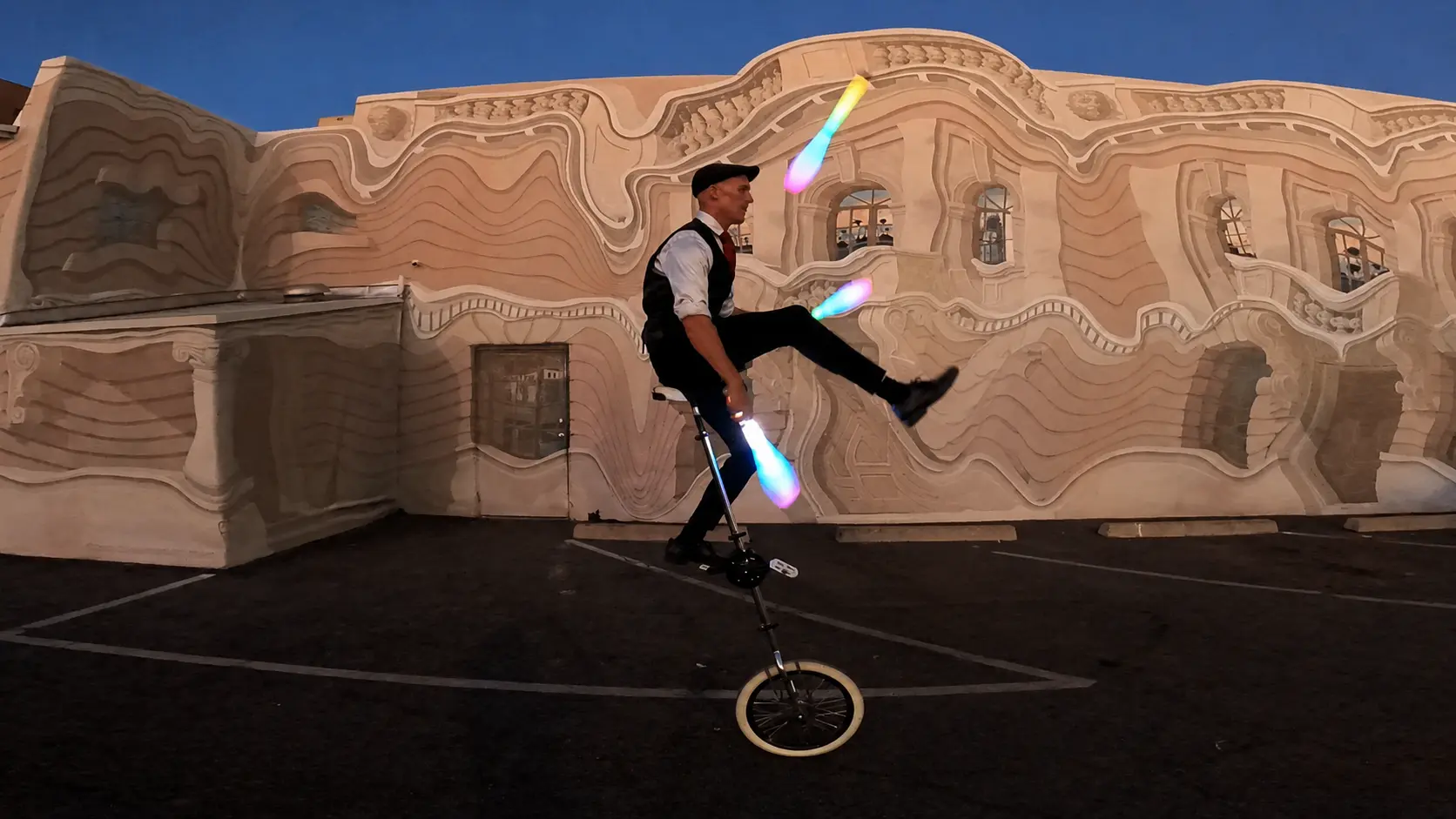 Dan juggling illuminated clubs while riding a giraffe unicycle